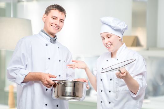 emotions of cooks, portrait with soup pot on the background of a commercial kitchen