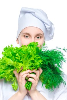 girl chef in a cap with a bunch of lettuce and dill on a white background