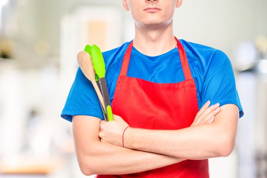 closeup of man's chest in apron with kitchen utensils