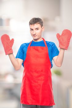 man in an apron and mittens for hot on a white background in the kitchen