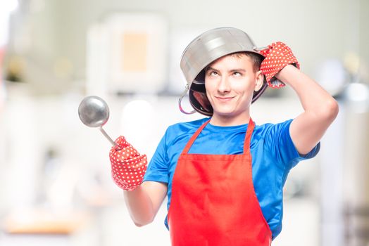 crazy man in a red apron put a pan on his head and posing in the kitchen