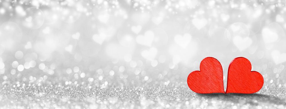 Two small handmade red wooden hearts on bright heart lights bokeh background