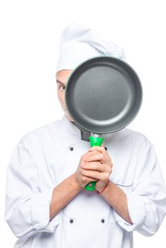 Chef looks out from behind the pan, the portrait is isolated