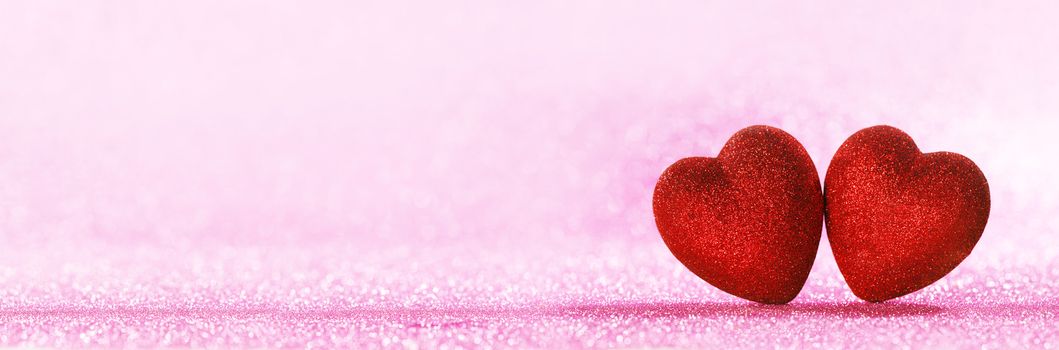 Two red glitter hearts on bright heart lights bokeh background