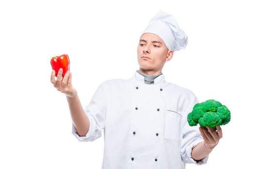 What to choose - pepper or broccoli - concept portrait of a cook with vegetables on a white background