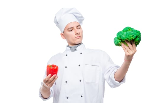 Difficult choice of pepper or broccoli - concept portrait of a chef with vegetables on a white background