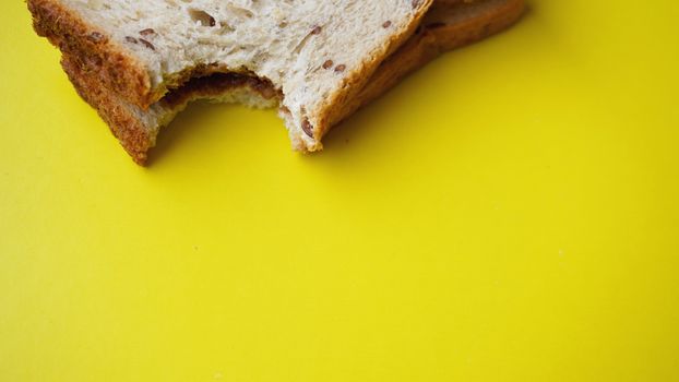Bitten Toast on yellow background - sandwich with chocolate spread. Background for breakfast. View from above - Copy space photography.