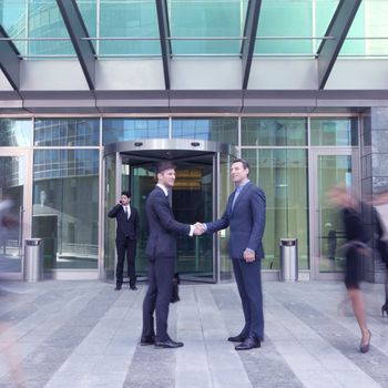 Business people shaking hands, finishing up a meeting outside office