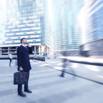 Handsome businessman talking on the cellphone outside office building