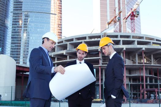 Architects with blueprint at skyscrapers background
