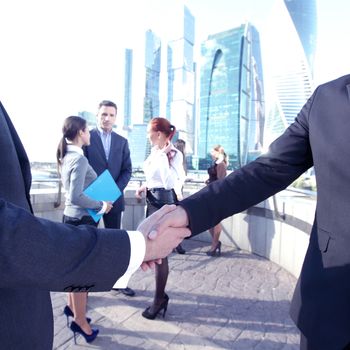 Business handshake, the deal Is finalized by group of people outside