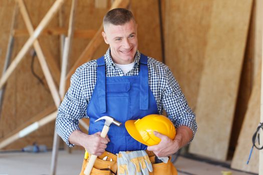 Construction worker at construction site holding hammer and hardhat