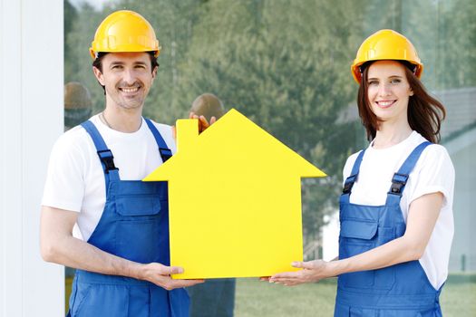 Construction workers showing house model symbol and friendly smiling