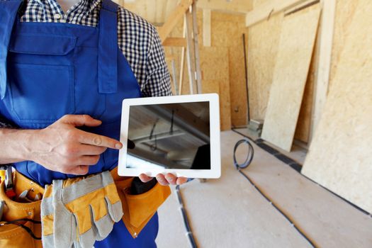 Construction worker pointing at digital tablet at construction site