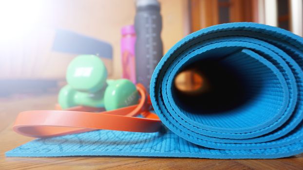 Close up of yoga, fitness floor mat at home in a roll. Yoga props and accessories, aqua turquoise mat. Healthy lifestyle concept