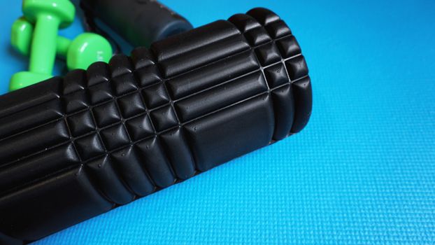 Foam Roller with green dumbbells Gym Fitness Equipment Blue background self Myofascial Release - MFR.
