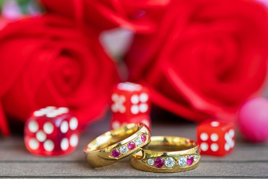 Close up shot wedding rings with dice and red roses