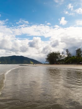 Sunny ia landscape at the beach with forest and clouds in the background.