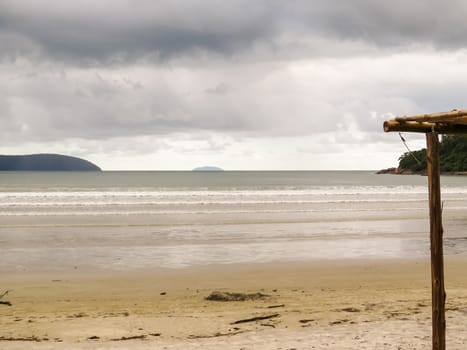 Empty beach landscape in day of heavy clouds, with island on the horizon.