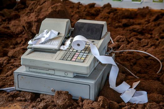 Old cash register with buttons and display. Cash register tape on old cash register. Cash register on brown ground background. Old cash register and cash register tape. 
