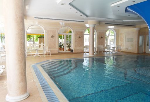 Luxurious pool interior design, sunlight from panoramic Windows, stylish columns and turquoise water.