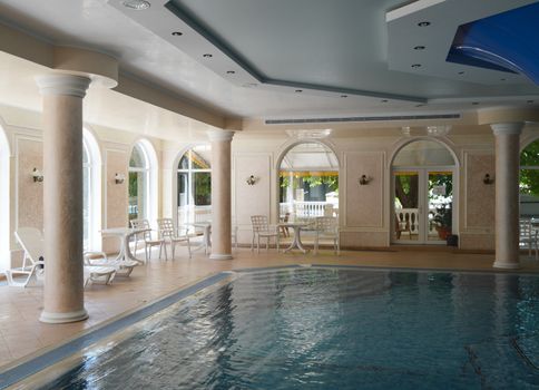 Luxurious pool interior design, sunlight from panoramic Windows, stylish columns and turquoise water.