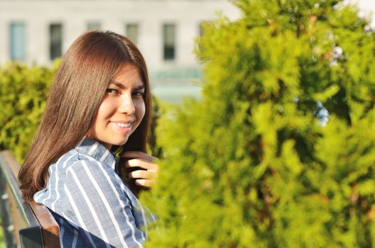 Beautiful portrait of a young girl who talks on the phone in the city Park near the beautiful green spaces