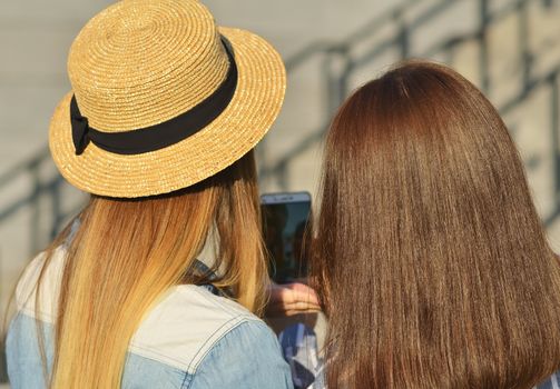 Two young girls taking selfies on the street