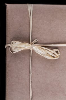 Old brown wrapping paper gift close-up with tied bow