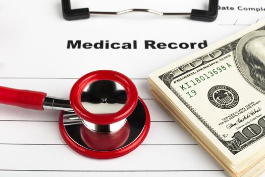 Money on a medical record clipboard with a red stethoscope isolated on white background