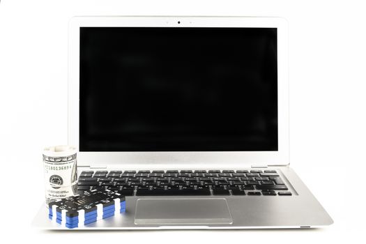 Dollars and casino chips on a silver laptop isolated on white background