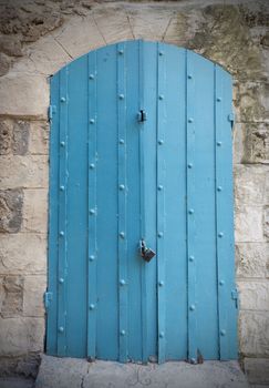 Old blue rusty metal entrance door in a old wall