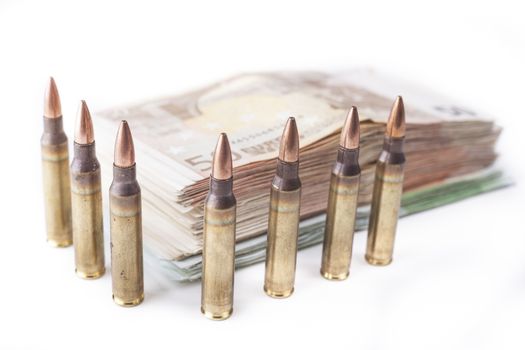 Multiple rifle bullets guarding a apile of  euro banknotes isolated on white
