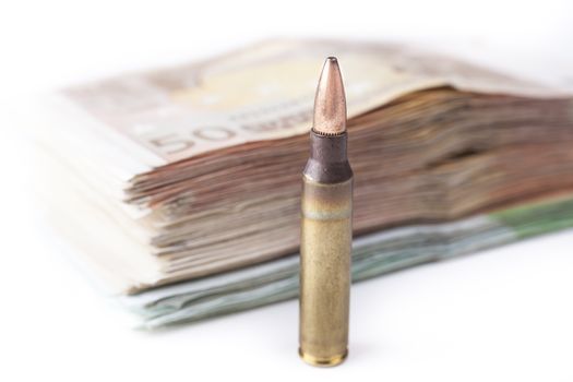 Single rifle bullet closeup with a pile of euro banknotes in the background isolated on white