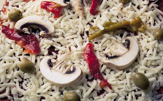 Raw pizza making closeup with green olives and peppers and cheese