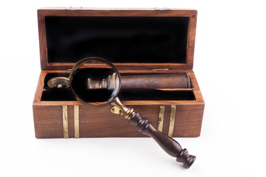 Open wood box with a telescope compass and a magnifying glass isolated on white