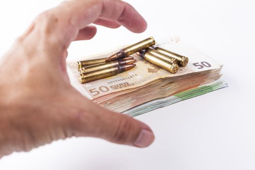 Hand grabbing a pil of bullets with euro banknotes isolated on white background