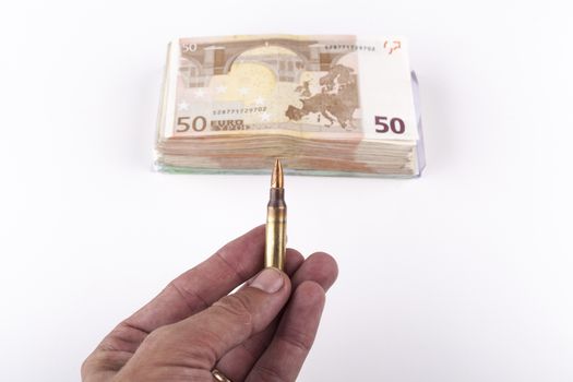 Man hand holding a rifle bullet with a bunch of euro banknotes isolated on white background
