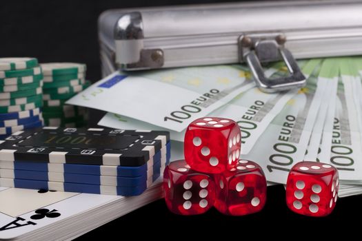 Casino chips and cards with red dices and euro banknotes on black background