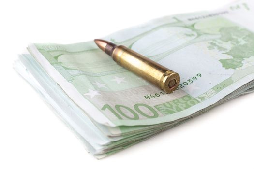Single rifle bullet closeup with a pile of a hundred euro banknotes in the background isolated on white