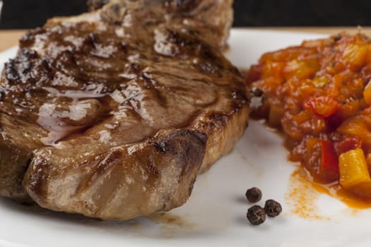 Grilled pork steak with vegetable garnish and some black peppers