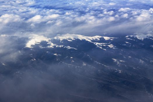 White snow on mountain peak with clouds aerial view