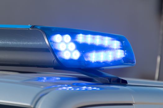 Detail shot of a glowing blue light on a police car on the street