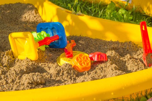set of colored plastic toys on the sand, children's sandbox in summer Sunny day.