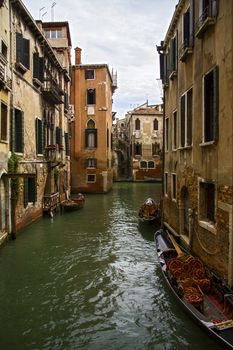 View of the street canal in Venice, Italy. Colorful facades of old Venice houses and gondolas on the green water.