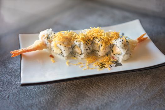 shrips sushi served  on rectangular white plate on dark gray stone background