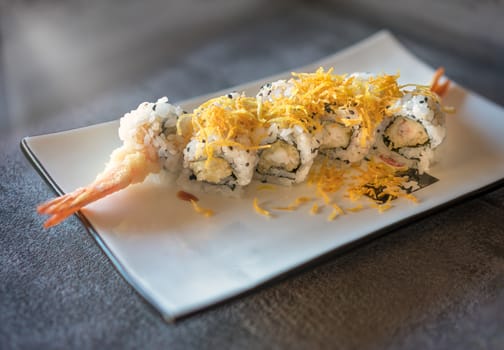 Prawn sushi served  on rectangular white plate on dark gray stone background