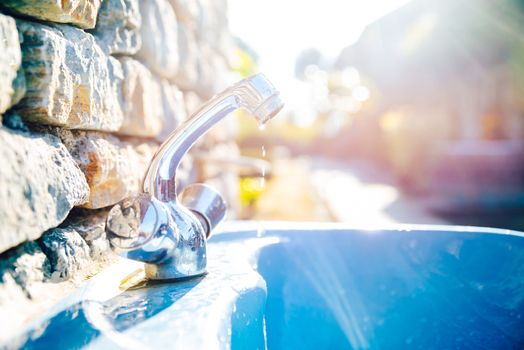 Outdoor washbasin in a garden, water dripping from tap. Waste concept.