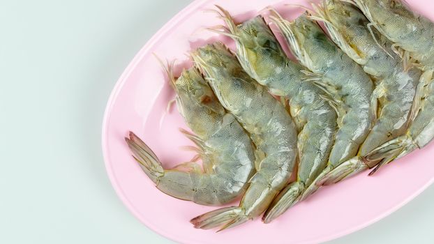 top view raw prawn on pink dish over white background