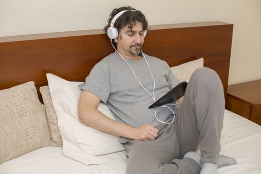 casual man working with a tablet pc in bed